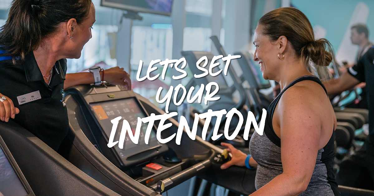 Woman and Personal Trainer looking at treadmill and talking about how to set intentions and goals for 2025